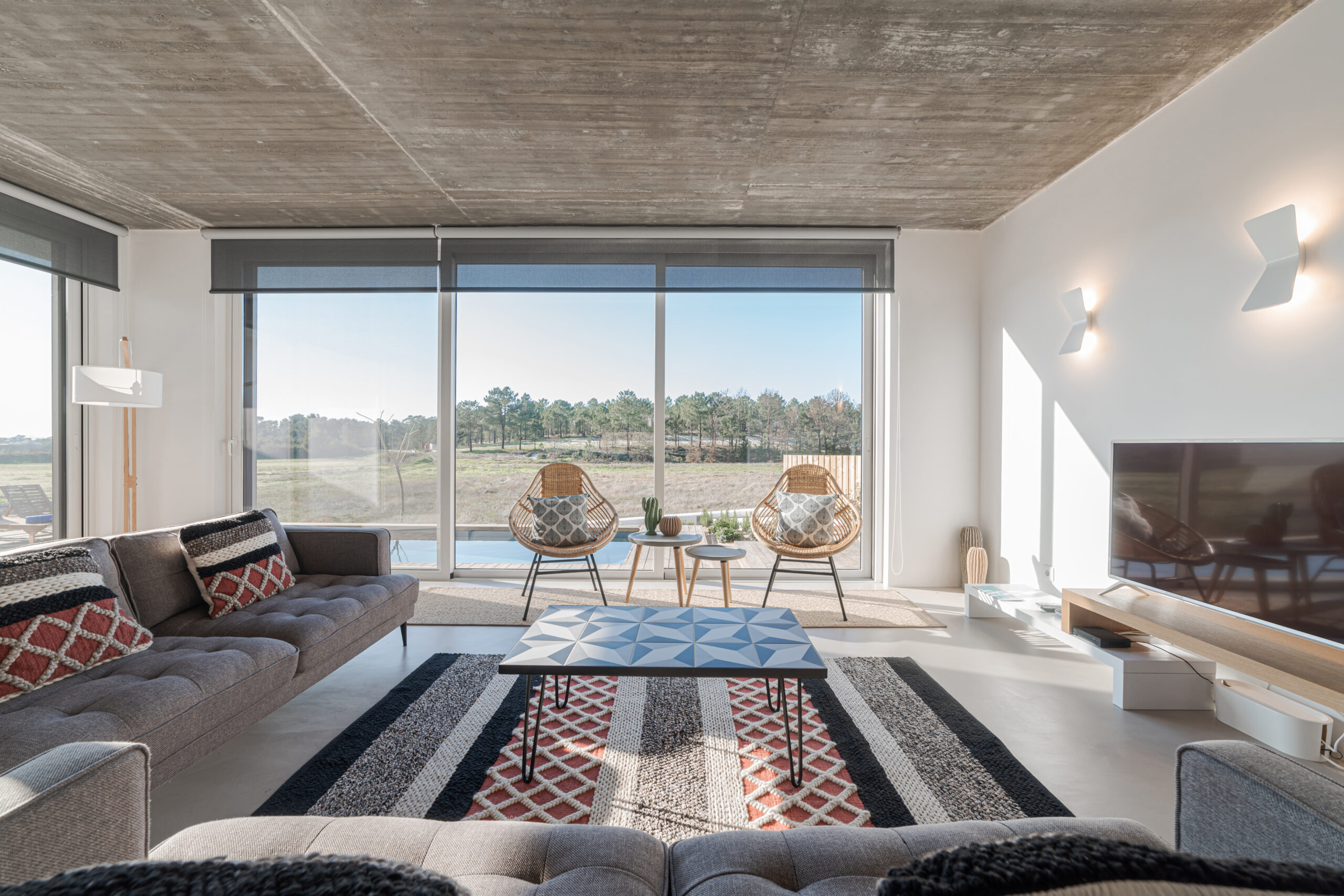 Moderna sala de estar con sofá y vistas a la piscina y la terraza.